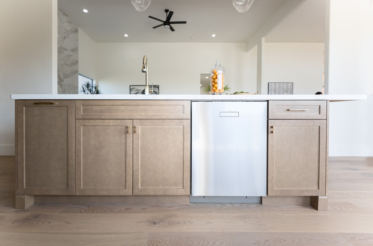 Beige kitchen island with white countertops, a sink and dishwasher.