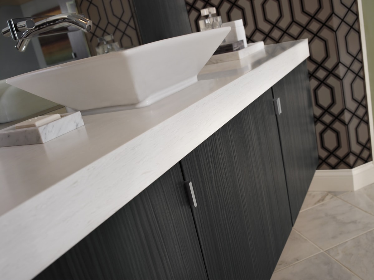 Black vertical grain wood vanity with a thick white countertop.