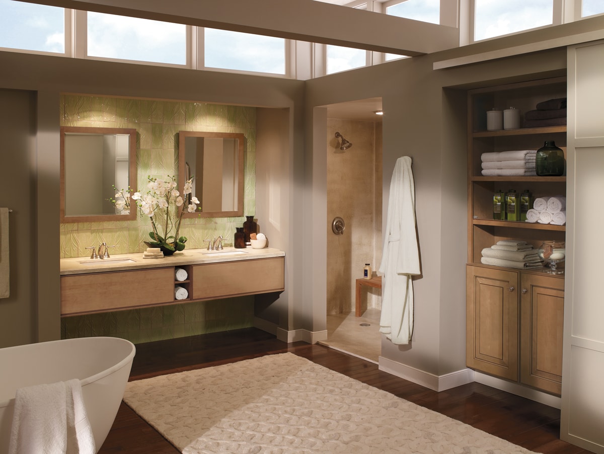 Light wood floating vanity and cabinetry with taupe walls and a light green tile backsplash.