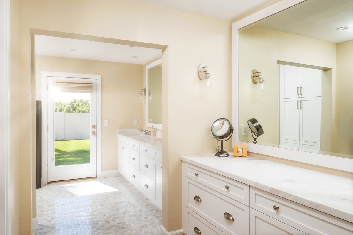 Two long white vanities running along a long cream-colored wall.