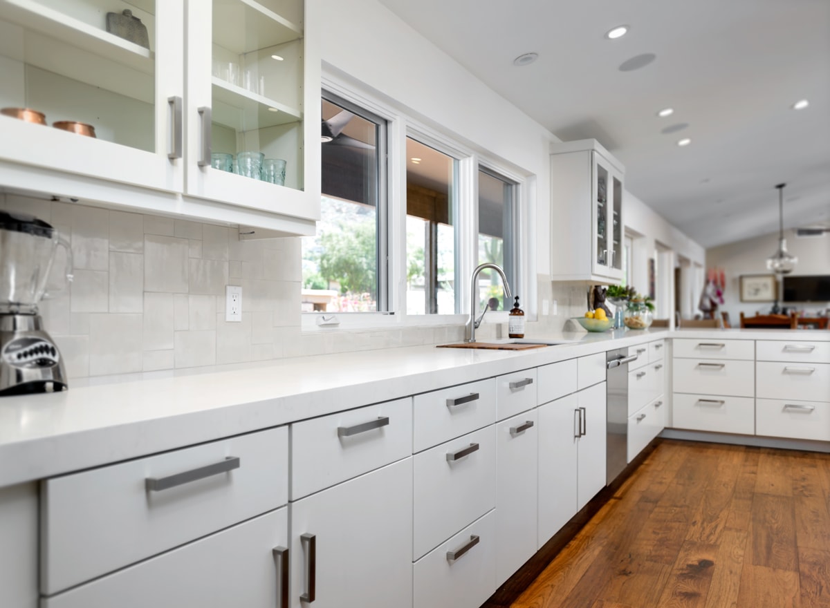 Long white wall with white slab style cabinets.