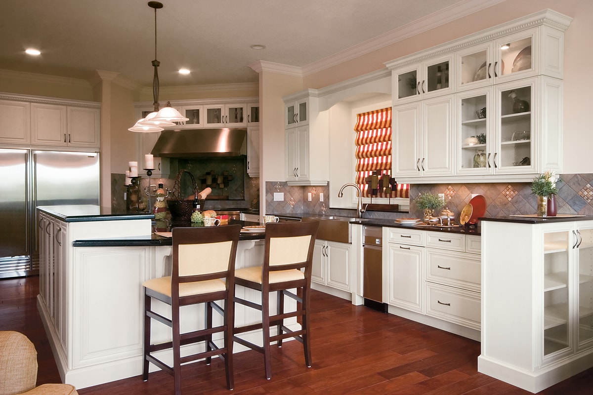 White cabinets with crown moulding and a stainless hood fan.