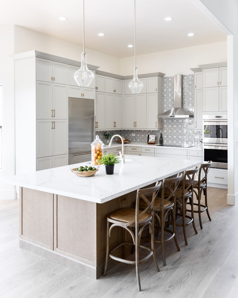 Warm light brown kitchen island with bar stools in a white kitchen.