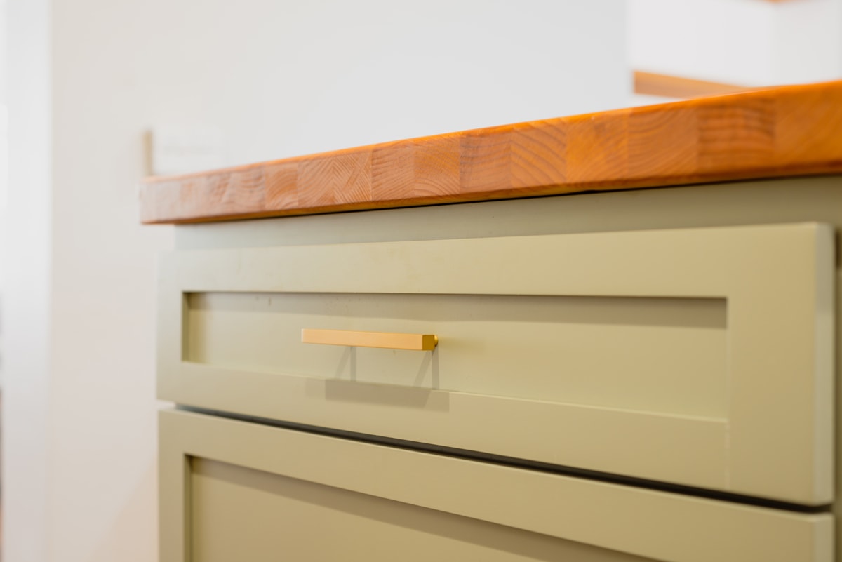 Close-up of a green cabinet with a butcher block style countertop.