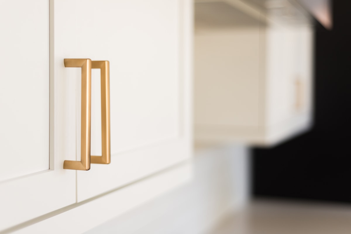 Close-up of white shaker cabinet with gold hardware pull.