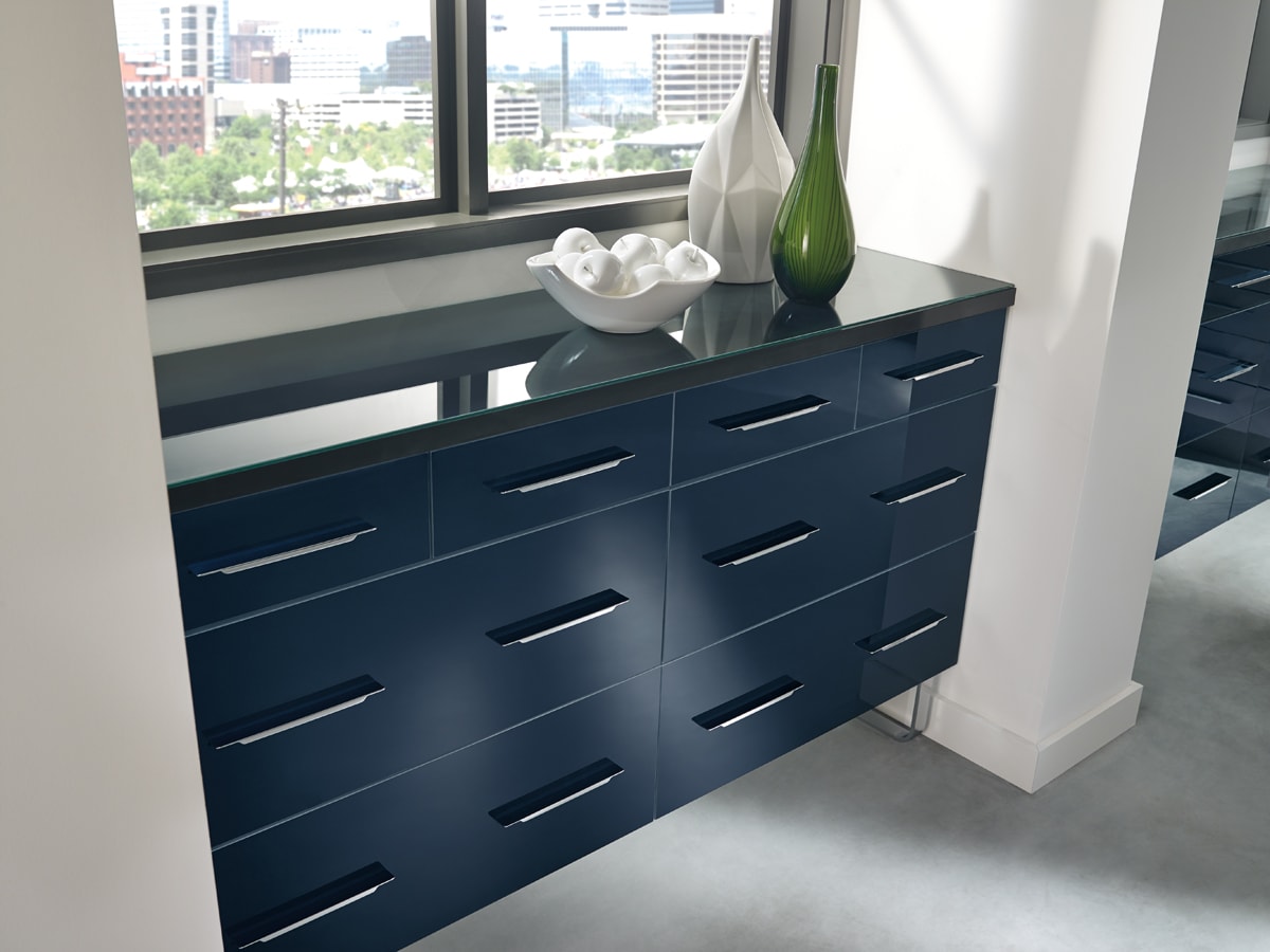 Shiny navy blue cabinetry underneath a window.